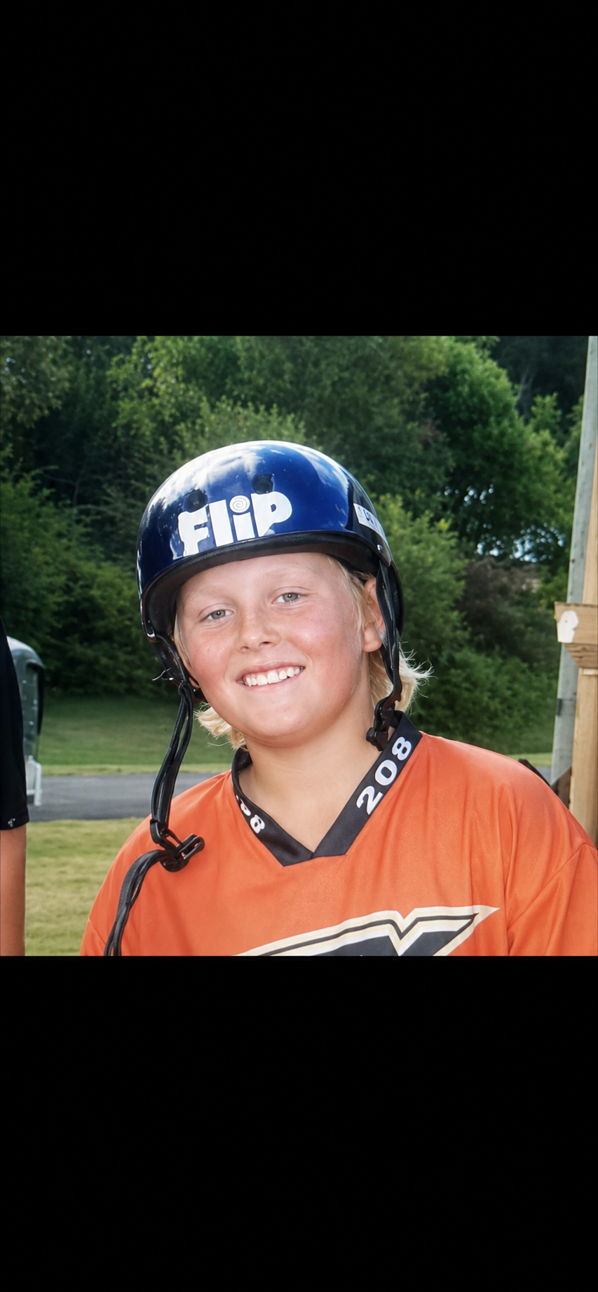 Shannon as a kid wearing a blue helmet and orange BMX jersey