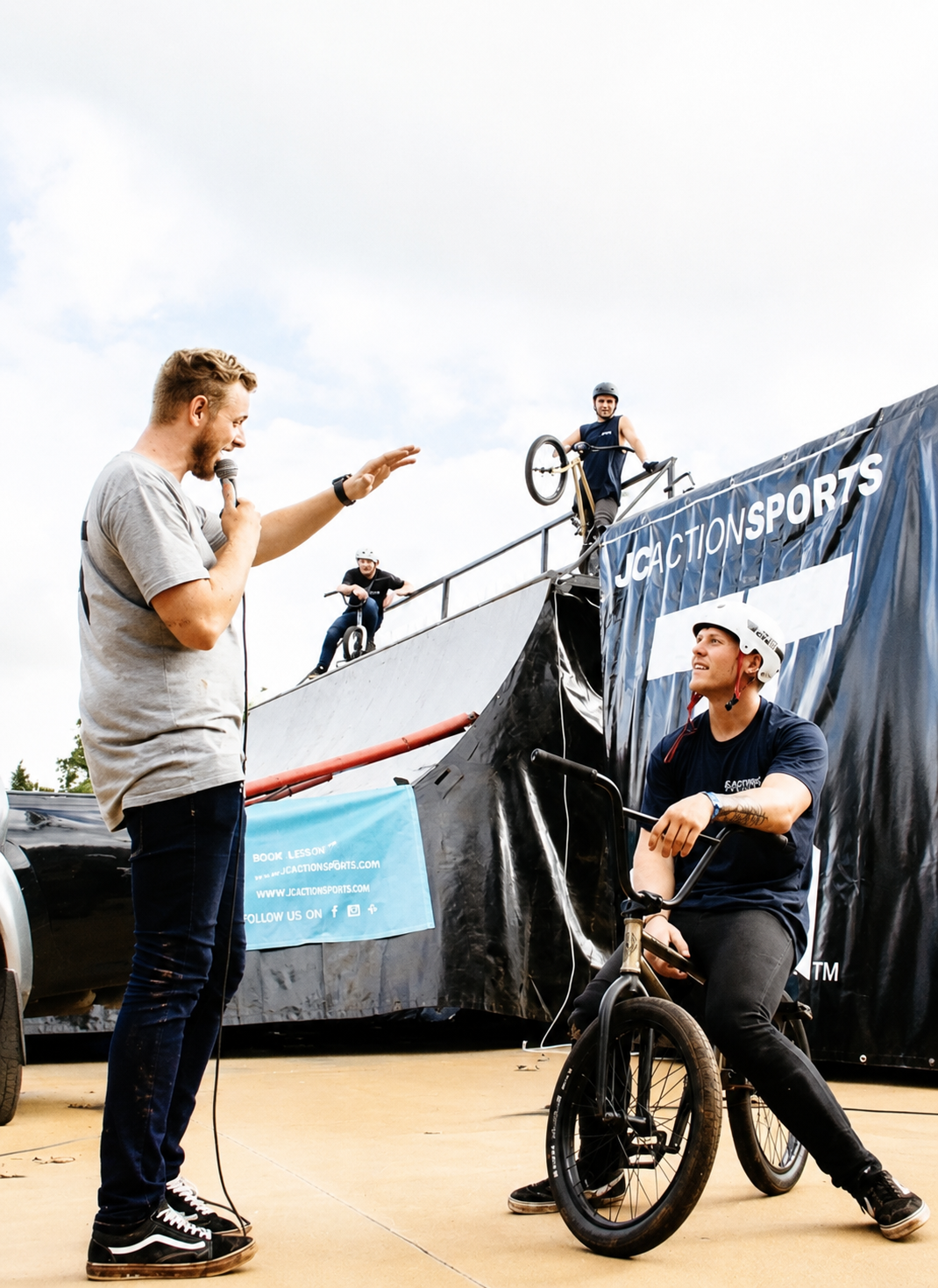 Shannon riding a BMX bike at an event while a speaker addresses the crowd